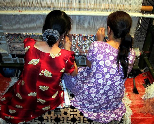 Mother and daughter working together on a rug in Uzbekistan.